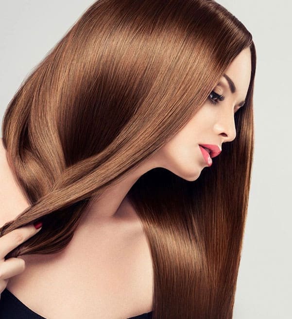 A woman with long brown hair is brushing her hair.