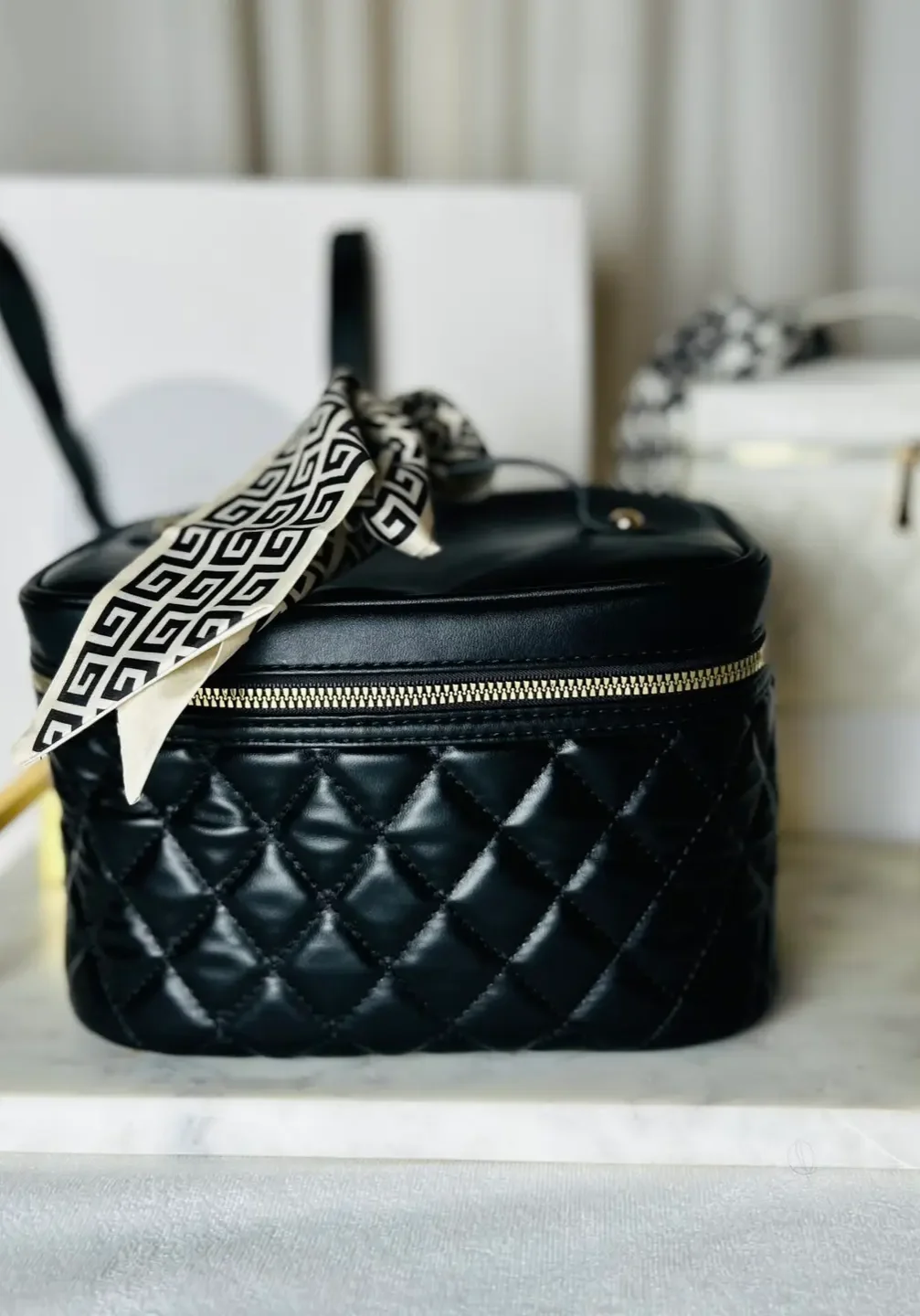 Black quilted cosmetic case on tray.